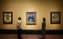 Visitors look at (from L) three paintings made by late Dutch artist Vincent Van Gogh 