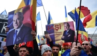 People wave Romanian flags and hold portraits of far-right presidential candidate Calin Georgescu during a protest in front of Romania's Constitutional Court in Budapest on January 10, 2024. (Photo by Daniel MIHAILESCU / AFP)