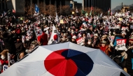 Supporters of impeached South Korea president Yoon Suk Yeol wave flags and shout slogans during a rally in Gwanghwamun in Seoul on January 11, 2025. (Photo by Anthony Wallace / AFP)