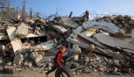 A boy plays with a rubber tyre next to the rubble of buildings destroyed in Israeli airstrike near the Nuseirat refugee camp in the central Gaza Strip on January 11, 2025. Photo by Eyad BABA / AFP