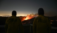 Firefighters monitor as the Palisades fire grows near the Mandeville Canyon neighborhood and Encino, California, on January 11, 2025. (Photo by Patrick T. Fallon / AFP)