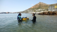 Free diver Zandile Ndlovu encourages a township youth to explore the marine world off Simonstown, near Cape Town, South Africa, August 22, 2021. Reuters/Mike Hutchings