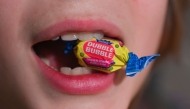 A boy holds a wrapped Dubble Bubble Bubble Gum candy in his mouth, a product that uses Red Dye # 3, in this illustration photograph on December 27, 2024. Photo by ROBERTO SCHMIDT / AFP