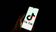 This photograph taken on April 19, 2024 shows a man holding a smartphone displaying the logo of Chinese social media platform Tiktok in an office in Paris. Photo by Antonin UTZ / AFP