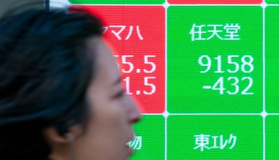 A woman walk past an electronic board showing the numbers of Nintendo's stock price (top, R) on the Tokyo Stock Exchange along a street in central Tokyo on January 17, 2025. Photo by Kazuhiro NOGI / AFP