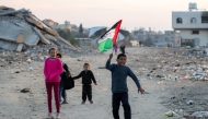 A boy runs with a Palestinian flag, at a camp for people displaced by conflict in Bureij in the central Gaza Strip on January 17, 2025. (Photo by Eyad Baba / AFP)