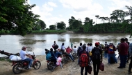 Displaced people from recent clashes between armed groups wait to cross the Tarra River, which divides Colombia and Venezuela, in Tibu, Norte de Santander department, Colombia, on January 19, 2025. (Photo by Schneyder Mendoza / AFP)