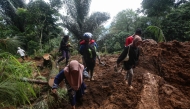 People walk through the site of a landslide triggered by heavy rain two days ago in Mudal village, near Pekalongan city in Central Java on January 22, 2025. (Photo by Devi Rahman / AFP)