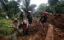 People walk through the site of a landslide triggered by heavy rain two days ago in Mudal village, near Pekalongan city in Central Java on January 22, 2025. (Photo by Devi Rahman / AFP)