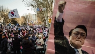 Supporters of South Korea's impeached President Yoon Suk Yeol (pictured on poster R) attend a rally on a road near the Constitutional Court in Seoul on January 23, 2025, after Yoon arrived at the court for hearings that will decide whether to remove him from office. (Photo by ANTHONY WALLACE / AFP)