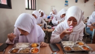 Students eat lunch on the first day of a free-meal program at 11 State Senior High School in East Jakarta on January 6, 2025. Photo by Aditya IRAWAN / AFP