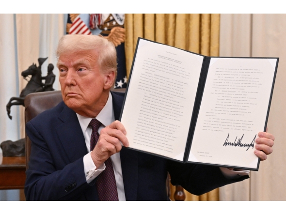 US President Donald Trump holds up an executive order he just signed to strenghten American leadership in digital financial technology, in the Oval Office of the White House in Washington, DC, on January 23, 2025. (Photo by Roberto Schmidt / AFP)