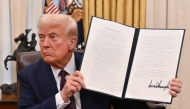 US President Donald Trump holds up an executive order he just signed to strenghten American leadership in digital financial technology, in the Oval Office of the White House in Washington, DC, on January 23, 2025. (Photo by Roberto Schmidt / AFP)