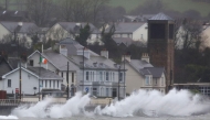 Waves break against the sea wall in Carnlough on the north east coast of Northern Ireland early in the morning of January 24, 2025, as storm Eowyn brings winds of 100 mph to the UK and Ireland. (Photo by PAUL FAITH / AFP)