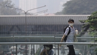 People in face masks are seen on a pedestrian skywalk amidst high levels of air pollution in Bangkok on January 24, 2025. (Photo by Lillian SUWANRUMPHA / AFP)