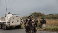 Uruguayan soldiers members of the United Nations Organization Stabilization Mission in the Democratic Republic of the Congo (MONUSCO) drive towards Goma as a soldier of the Armed forces of the Democratic republic of Congo (FARDC) walks along the road leading to the entrance of the town of Sake, 25km north-west of Goma, on January 23, 2025. Photo by Michael Lunanga / AFP.