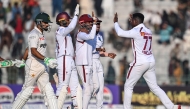 West Indies' Kevin Sinclair (R) celebrates with his teammates after taking the wicket of Pakistan's Babar Azam (L) during the second day of the second Test cricket match between Pakistan and West Indies at the Multan Cricket Stadium in Multan on January 26, 2025. (Photo by Farooq NAEEM / AFP)