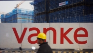 This photo taken on March 31, 2024 shows a worker driving past residential buildings under construction by Chinese real estate developer Vanke in Hangzhou, in eastern China's Zhejiang province. Photo by AFP