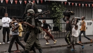 A member of the M23 armed group walk alongside residents through a street of the Keshero neighborhood in Goma, on January 27, 2025. (Photo by -STR / AFP)

