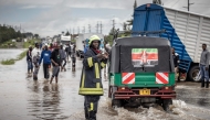 A Kenyan firefighter gives directions to commuters as residents inspect a road heavily affected by floods following torrential rains in Kitengela, on May 1, 2024. Photo by LUIS TATO / AFP