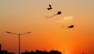 Kites are silhouetted against the setting sun during the 'Qatar Kite Festival 2025' at Old Doha Port in Doha on January 21, 2025. (Photo by Karim JAAFAR / AFP)