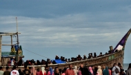 People gather around a boat carrying newly-arrived Rohingya refugees at Leuge Beach in Indonesia's Aceh province on January 29, 2025. (Photo by Cek MAD / AFP)