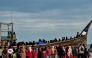 People gather around a boat carrying newly-arrived Rohingya refugees at Leuge Beach in Indonesia's Aceh province on January 29, 2025. (Photo by Cek MAD / AFP)