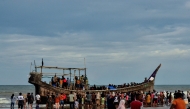 People gather around a boat carrying newly-arrived Rohingya refugees, after authorities prevented the refugees from disembarking and ordered them to remain on board the vessel, at Leuge Beach in Indonesia's Aceh province on January 29, 2025. (Photo by Cek MAD / AFP)
