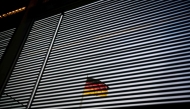 The German national flag is seen through a Venetian blind at the Bundestag (lower house of parliament) in Berlin on January 31, 2025. (Photo by Tobias SCHWARZ / AFP)