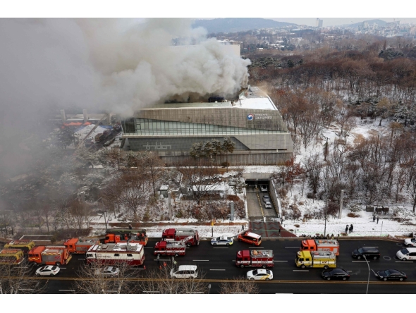 Fire engines are seen on a road as smoke rises from the roof of the National Hangeul Museum in Seoul on February 1, 2025. (Photo by YONHAP / AFP) 