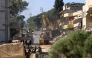 People and soldiers watch an excavator clearing the rubble from a street in the southern Lebanese border town of Aitaroun, as inhabitants return following the pullout of Israeli troops and the deployment of the Lebanese army, on February 2, 2025. (Photo by Mahmoud ZAYYAT / AFP)