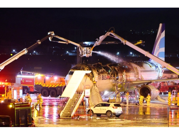 Firefighters work to extinguish a fire that broke out on an Air Busan passenger plane bound for Hong Kong, at Gimhae International Airport in Busan on January 28, 2025. Photo by YONHAP / AFP