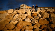 A couple sits on a boulder dyke at sunset along the Atlantic Ocean in Lacanau, southwestern France on February 1, 2025. (Photo by Christophe ARCHAMBAULT / AFP)