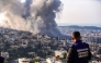 A journalist looks on as smoke billows from the site of several explosions during an Israeli raid in the occupied West Bank city of Jenin on February 2, 2025. (Photo by MOHAMMAD MANSOUR / AFP)
