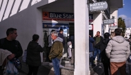 People queue to buy ferry tickets to leave the Greek Island of Santorini at a travel agency in the town of Fira on February 4, 2025. (Photo by Aris Messinis / AFP)