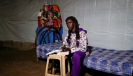 Teenage Sudanese rapper Hanim Mohamed (14), also known as Nana, poses for a picture while writing in a notebook inside a tent at the Zaeem al-Azhary School Shelter in Port Sudan on January 15, 2025. (Photo by AFP)
