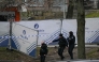 Police officers walk near a police fence blocking off an investigation area at the 