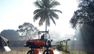 This photograph taken on February 3, 2025 shows workers at agritech startup Niqo Robotics, riding a tractor with AI-powered spot sprayer at a testing facility on the outskirts of Bengaluru. Photo by AFP