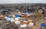 Palestinians walk around their tents, set up amid heavily damaged buildings in Jabalia, in the northern Gaza Strip, on February 6, 2025. (Photo by Bashar TALEB / AFP)
