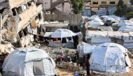 This view shows the tents of displaced Palestinians erected by a collapsed building in Gaza City on December 11, 2024. (Photo by Omar Al-Qattaa / AFP)