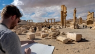 A visitor sketches while seated before the Great Colonnade (Decumanus Maximus) at the ancient ruins of Palmyra in central Syria on February 7, 2025. (Photo by Omar Haj Kadour / AFP)