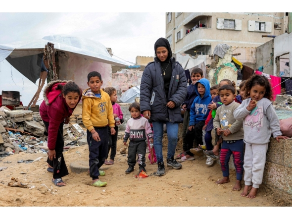 Children play with marbles near destroyed buildings at the Shati camp for Palestinian refugees north of Gaza City on February 11, 2025 amid the current ceasefire deal in the war between Israel and Hamas. (Photo by Bashar Taleb / AFP)