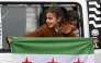 A girl holds an independence-era Syrian flag out of the window of a bus carrying displaced Syrians returning home after years of displacement in the northern Aleppo province, at the entrance of the central city of Homs on February 10, 2025. (Photo by Louai Beshara / AFP)