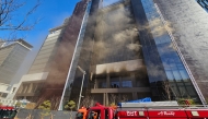 Firefighters work at the scene of a fire at a construction site of the Banyan Tree Hotel in the southern port city of Busan on February 14, 2025. (Photo by YONHAP / AFP) 