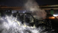 Smoke billows from the burnt remains of a UNIFIL vehicle, set ablaze by protesters, on the road leading to Beirut's international airport on February 14, 2025. (Photo by Ibrahim Amro / AFP)