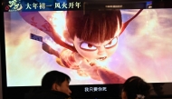 People wait as a screen displays a scene from the Ne Zha 2 animated film at a movie theatre in Beijing on February 16, 2025. (Photo by Pedro PARDO / AFP)
