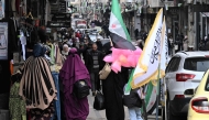 People walk past shops in Homs on February 10, 2025. (Photo by Louai Beshara / AFP)