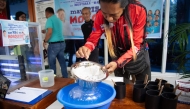 A village officer examines a strainer filled with mosquito larvaes for counting at the start of 