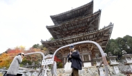 A large pair of glasses frames is seen in front of the three-story pagoda at Tsubosakadera temple in Takatori, Nara Prefecture. MUST CREDIT: The Japan News