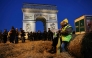 (Files) French farmers are seen sitting on a bale of hay as policemen secure the area in front of the Arc de Triomphe near the Champs-Elysees Avenue during a protest by the French farmers' union in Paris on March 1, 2024. (Photo by Thomas Samson / AFP)